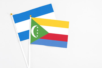 Comoros and Nicaragua stick flags on white background. High quality fabric, miniature national flag. Peaceful global concept.White floor for copy space.