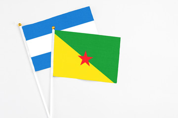 French Guiana and Nicaragua stick flags on white background. High quality fabric, miniature national flag. Peaceful global concept.White floor for copy space.