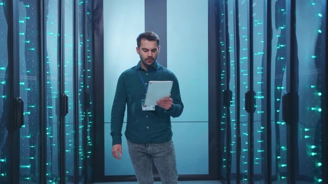 Caucasian IT engineer activating digital database server room with tablet. Bearded specialist inspecting rack internet servers at data center computer security. Zoom out.