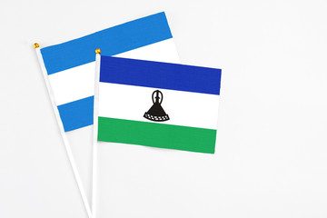 Lesotho and Nicaragua stick flags on white background. High quality fabric, miniature national flag. Peaceful global concept.White floor for copy space.