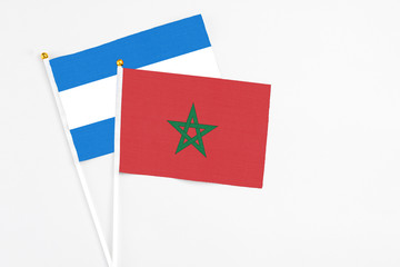 Morocco and Nicaragua stick flags on white background. High quality fabric, miniature national flag. Peaceful global concept.White floor for copy space.