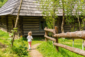 Child girl running on countryside road to house