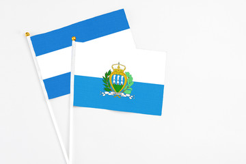San Marino and Nicaragua stick flags on white background. High quality fabric, miniature national flag. Peaceful global concept.White floor for copy space.
