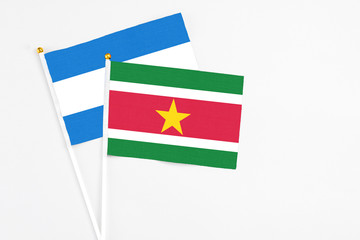 Suriname and Nicaragua stick flags on white background. High quality fabric, miniature national flag. Peaceful global concept.White floor for copy space.