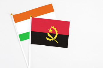 Angola and Niger stick flags on white background. High quality fabric, miniature national flag. Peaceful global concept.White floor for copy space.