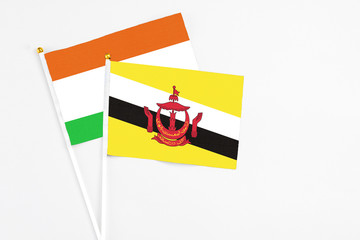 Brunei and Niger stick flags on white background. High quality fabric, miniature national flag. Peaceful global concept.White floor for copy space.