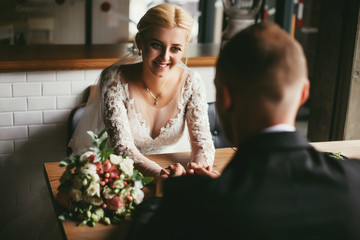 Bride and groom drinking coffee indoor cafe. newlyweds sitting opposite each other