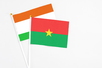 Burkina Faso and Niger stick flags on white background. High quality fabric, miniature national flag. Peaceful global concept.White floor for copy space.