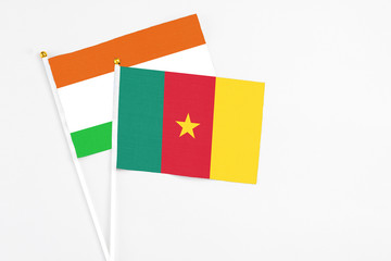 Cameroon and Niger stick flags on white background. High quality fabric, miniature national flag. Peaceful global concept.White floor for copy space.
