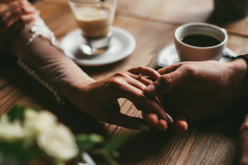 Bride and groom holding hands on wooden table indoor cafe