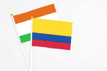 Colombia and Niger stick flags on white background. High quality fabric, miniature national flag. Peaceful global concept.White floor for copy space.