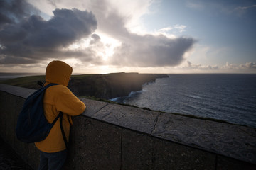 Man with yellow jacket looking at horizon on Cliffs of Moher