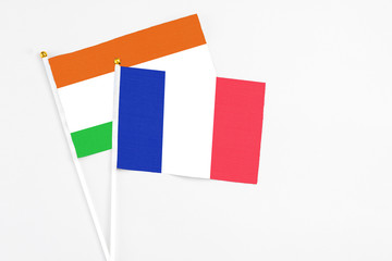 France and Niger stick flags on white background. High quality fabric, miniature national flag. Peaceful global concept.White floor for copy space.