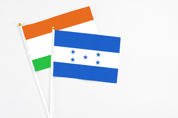 Honduras and Niger stick flags on white background. High quality fabric, miniature national flag. Peaceful global concept.White floor for copy space.