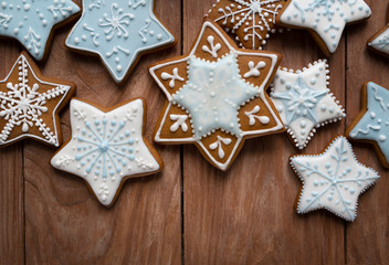 Obraz na płótnie Canvas Homemade gingersnaps covered with icing on the wooden background; delicious cookies with Christmas shapes