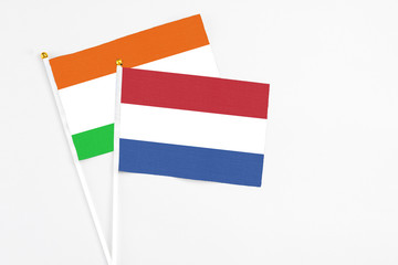 Netherlands and Niger stick flags on white background. High quality fabric, miniature national flag. Peaceful global concept.White floor for copy space.