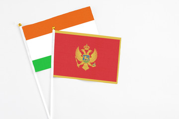 Montenegro and Niger stick flags on white background. High quality fabric, miniature national flag. Peaceful global concept.White floor for copy space.