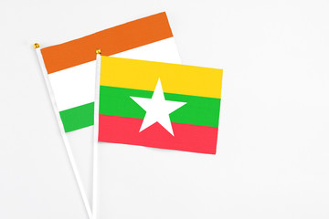 Myanmar and Niger stick flags on white background. High quality fabric, miniature national flag. Peaceful global concept.White floor for copy space.