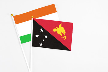 Papua New Guinea and Niger stick flags on white background. High quality fabric, miniature national flag. Peaceful global concept.White floor for copy space.