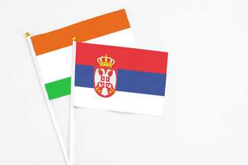 Serbia and Niger stick flags on white background. High quality fabric, miniature national flag. Peaceful global concept.White floor for copy space.