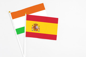 Spain and Niger stick flags on white background. High quality fabric, miniature national flag. Peaceful global concept.White floor for copy space.