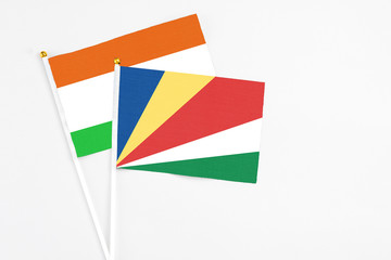 Seychelles and Niger stick flags on white background. High quality fabric, miniature national flag. Peaceful global concept.White floor for copy space.