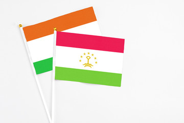 Tajikistan and Niger stick flags on white background. High quality fabric, miniature national flag. Peaceful global concept.White floor for copy space.