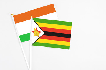 Zimbabwe and Niger stick flags on white background. High quality fabric, miniature national flag. Peaceful global concept.White floor for copy space.