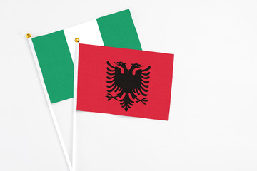 Albania and Nigeria stick flags on white background. High quality fabric, miniature national flag. Peaceful global concept.White floor for copy space.