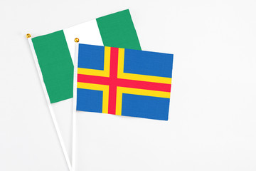 Aland Islands and Nigeria stick flags on white background. High quality fabric, miniature national flag. Peaceful global concept.White floor for copy space.