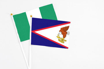 American Samoa and Nigeria stick flags on white background. High quality fabric, miniature national flag. Peaceful global concept.White floor for copy space.