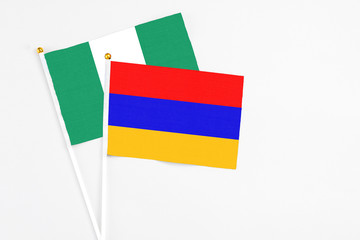 Armenia and Nigeria stick flags on white background. High quality fabric, miniature national flag. Peaceful global concept.White floor for copy space.