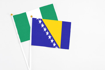 Bosnia Herzegovina and Nigeria stick flags on white background. High quality fabric, miniature national flag. Peaceful global concept.White floor for copy space.