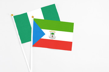Equatorial Guinea and Nigeria stick flags on white background. High quality fabric, miniature national flag. Peaceful global concept.White floor for copy space.