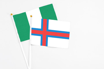 Faroe Islands and Nigeria stick flags on white background. High quality fabric, miniature national flag. Peaceful global concept.White floor for copy space.