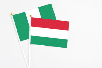 Hungary and Nigeria stick flags on white background. High quality fabric, miniature national flag. Peaceful global concept.White floor for copy space.