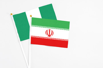 Iran and Nigeria stick flags on white background. High quality fabric, miniature national flag. Peaceful global concept.White floor for copy space.