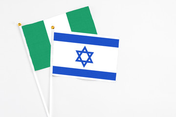Israel and Nigeria stick flags on white background. High quality fabric, miniature national flag. Peaceful global concept.White floor for copy space.