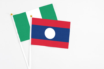 Laos and Nigeria stick flags on white background. High quality fabric, miniature national flag. Peaceful global concept.White floor for copy space.