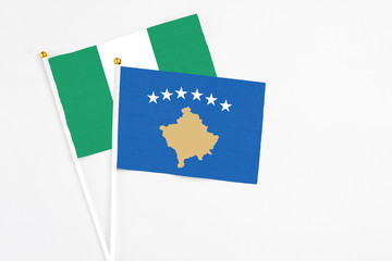 Kosovo and Nigeria stick flags on white background. High quality fabric, miniature national flag. Peaceful global concept.White floor for copy space.
