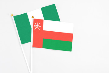 Oman and Nigeria stick flags on white background. High quality fabric, miniature national flag. Peaceful global concept.White floor for copy space.
