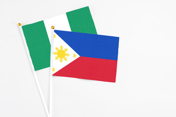 Philippines and Nigeria stick flags on white background. High quality fabric, miniature national flag. Peaceful global concept.White floor for copy space.