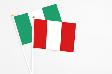 Peru and Nigeria stick flags on white background. High quality fabric, miniature national flag. Peaceful global concept.White floor for copy space.