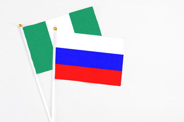 Russia and Nigeria stick flags on white background. High quality fabric, miniature national flag. Peaceful global concept.White floor for copy space.