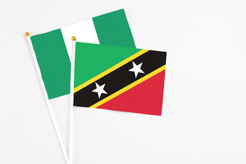 Saint Kitts And Nevis and Nigeria stick flags on white background. High quality fabric, miniature national flag. Peaceful global concept.White floor for copy space.