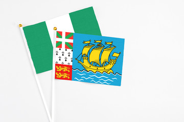 Saint Pierre And Miquelon and Nigeria stick flags on white background. High quality fabric, miniature national flag. Peaceful global concept.White floor for copy space.