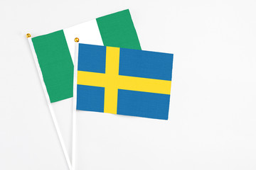 Sweden and Nigeria stick flags on white background. High quality fabric, miniature national flag. Peaceful global concept.White floor for copy space.
