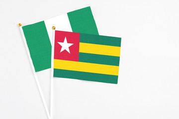Togo and Nigeria stick flags on white background. High quality fabric, miniature national flag. Peaceful global concept.White floor for copy space.