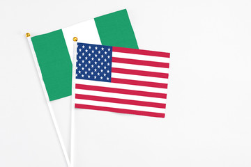 United States and Nigeria stick flags on white background. High quality fabric, miniature national flag. Peaceful global concept.White floor for copy space.