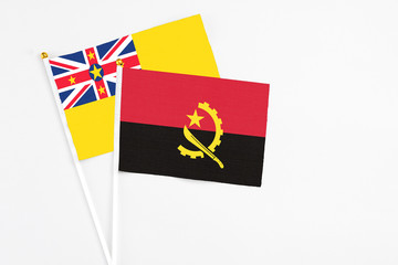Angola and Niue stick flags on white background. High quality fabric, miniature national flag. Peaceful global concept.White floor for copy space.